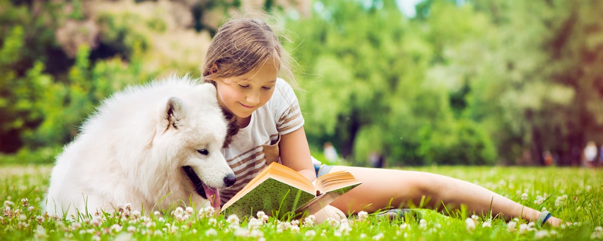 girl reading to white dog